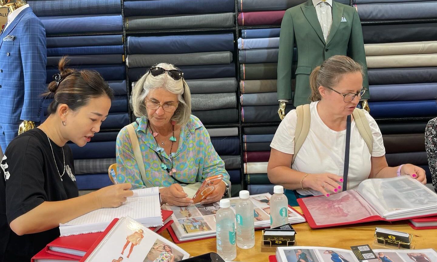Hoi An tailor consulting customers on outfit selection 